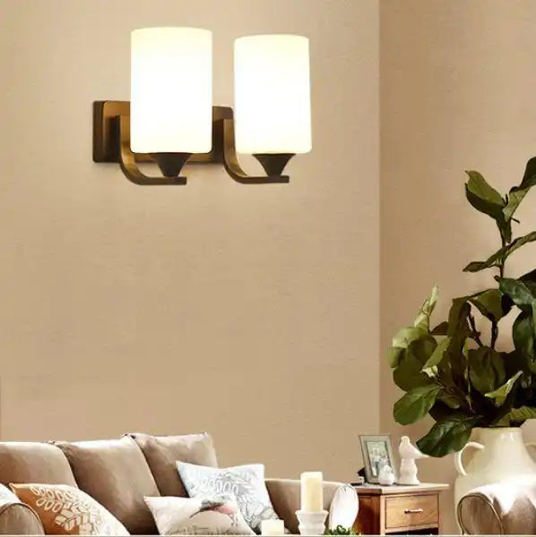 Double wall sconce with cylindrical frosted glass shades mounted on bronze-toned brackets.